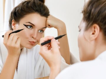 Frau trägt Eyeliner auf und schaut unzufrieden | © AdobeStock/blackday