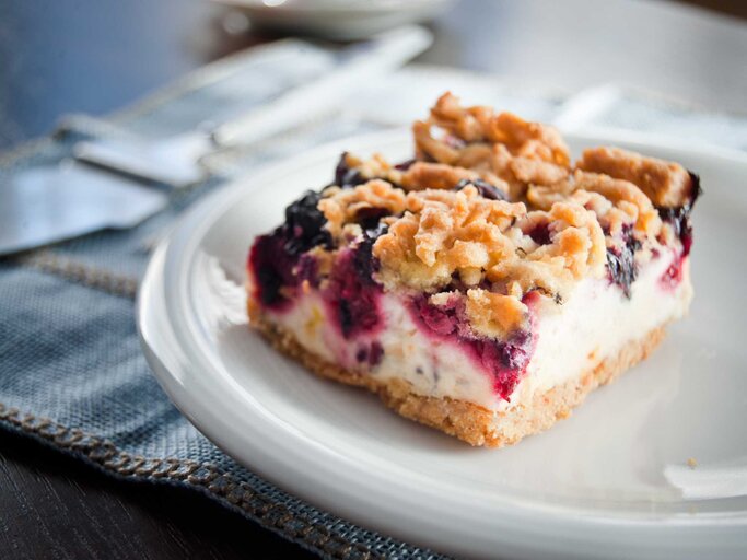 Ein Stück Schmand-Streusel-Kuchen auf einem Teller. Seitlich fotografiert. | © Getty Images/thepiwko