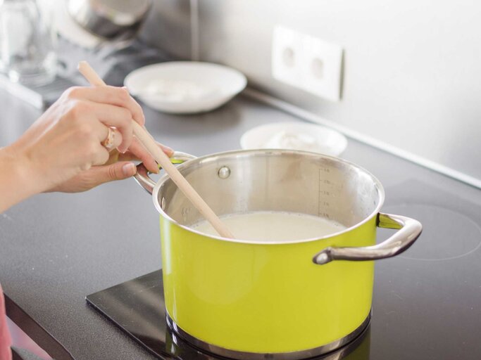 Frau rührt Milch im Kochtopf um | © Adobe Stock/ Inna Dodor