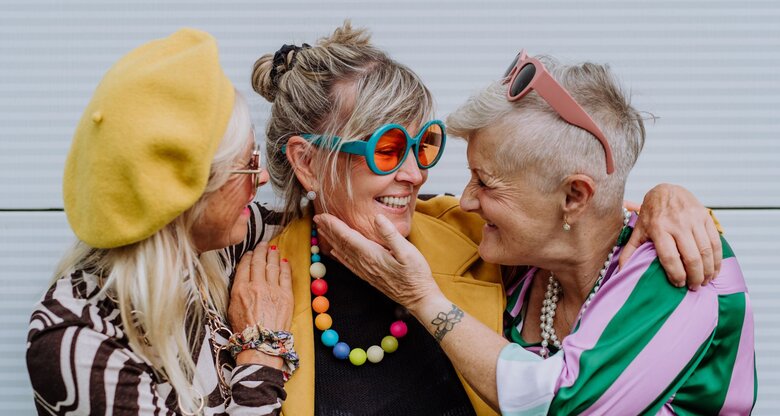 Drei Freundinnen umarmen sich und lachen miteinander. | © Getty Images / Halfpoint Images