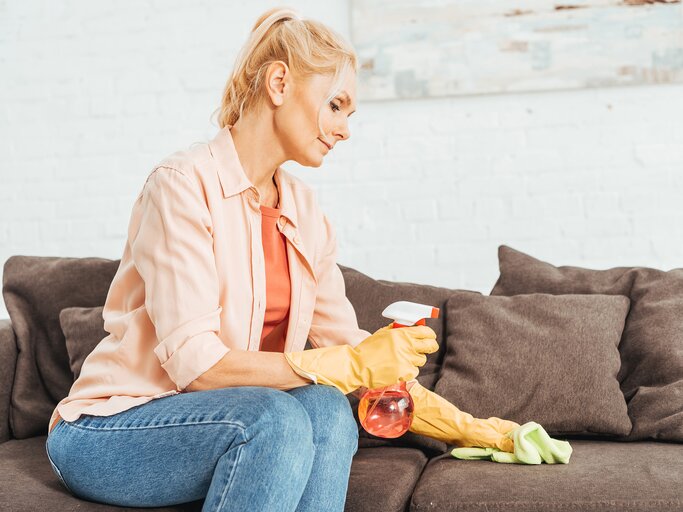 Frau reinigt Sofa mit Lappen und Putzmittel | © AdobeStock/LIGHTFIELD STUDIOS