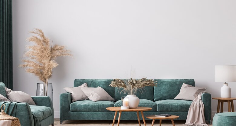 Wohnzimmer mit weißen Wänden, grünem Sofa und hellbraunen Holztischen | © AdobeStock/lilasgh