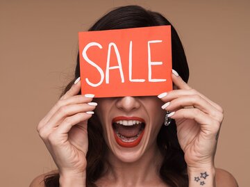 Schreiende Frau hält Schild mit der Aufschrift "Sale" vor das Gesicht | © AdobeStock/Drobot Dean