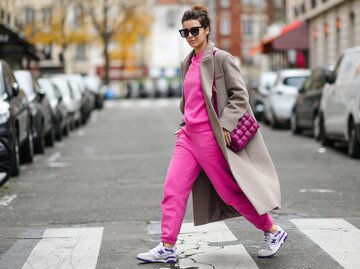 Streetstyle von Katie Giorgadze in pinker Jogginghose, pinkem Sweatshirt, beigem Mantel und Sneakers | © Getty Images/Edward Berthelot