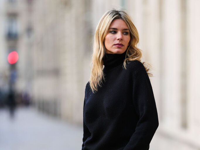 Streetstyle von Frau mit langen, blonden Haaren in schwarzem Rollkragenpullover | © Getty Images/Edward Berthelot