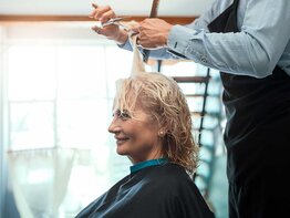 Ältere Frau sitzt beim Friseur und bekommt die Haare geschnitten.  | © Getty Images / Nastasic