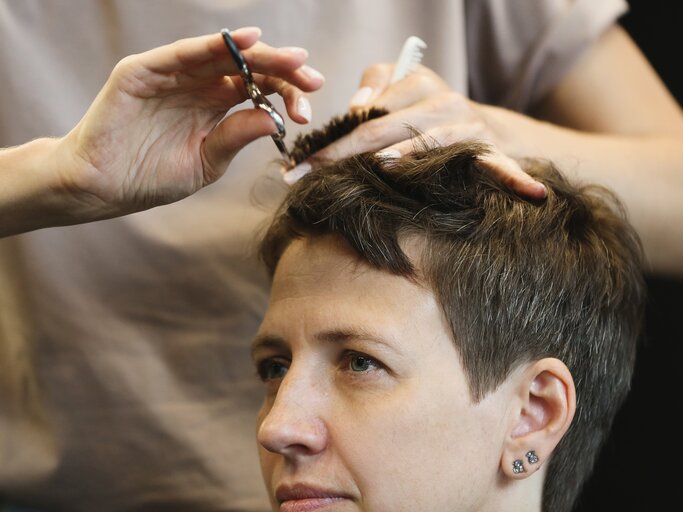 Nahaufnahme von Händen einer Friseurin, die einer Frau einen Pixie Cut schneidet | © GettyImages/Elena Popova