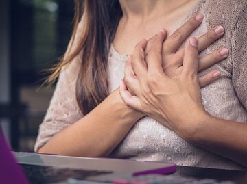 Junge Frau in rosa Pullover fässt sich mit beiden Händen ans Herz, | © spukkato, iStock