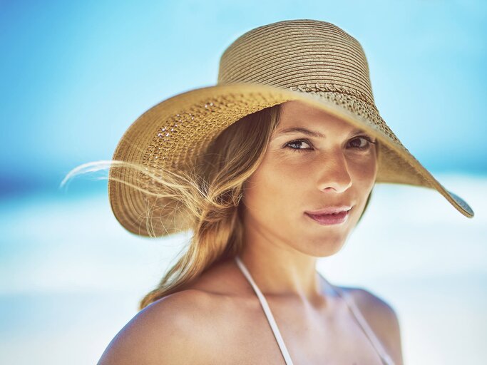 Frau mit Sonnenhut am Strand | © iStock | PeopleImages