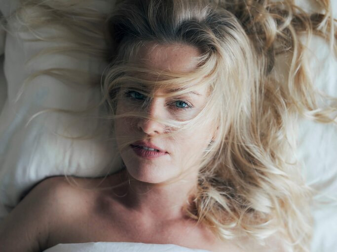 Frau liegt mit zerzausten Haaren im Bett | © gettyimages.de /  FreshSplash