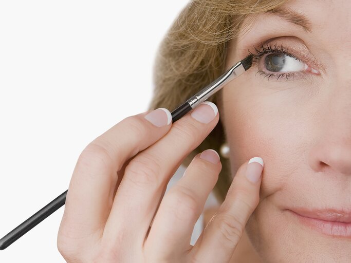 Reife Frau schminkt sich mit Eyeliner | © Getty Images/Glow Images