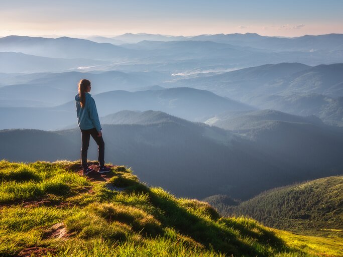 Frau steht oben am Berg | © AdobeStock/den-belitsky