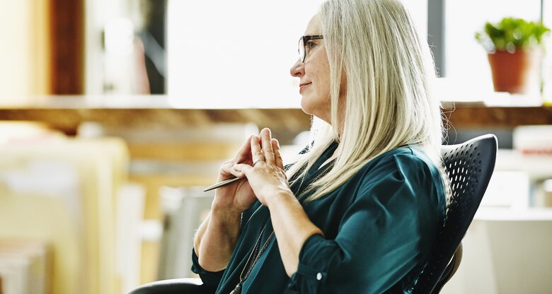 Frau sitzt im Bürostuhl und denkt nach | © GettyImages/ThomasBrawick