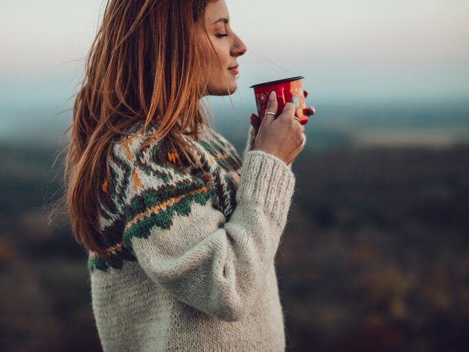 Frau im winterlichen Ambiente trinkt einen Kaffee | © GettyImages/Jasmina007