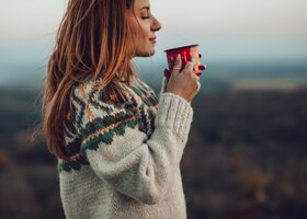 Frau im winterlichen Ambiente trinkt einen Kaffee