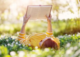 Frau liest Buch in frühlingshafter Blumenwiese